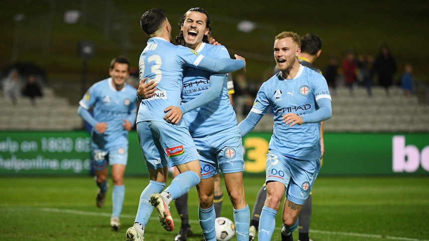 Two Melbourne City A-League players embrace as they celebrate a goal.