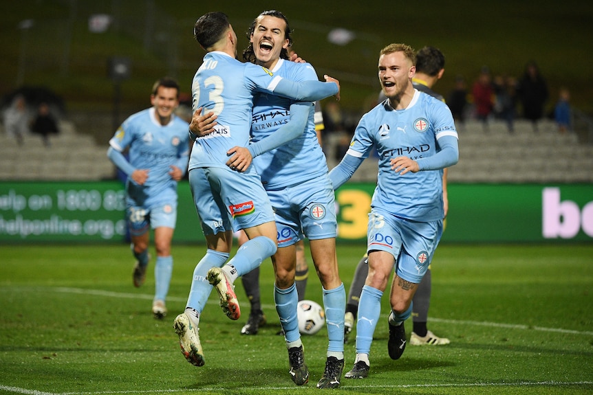 Two Melbourne City A-League players embrace as they celebrate a goal.