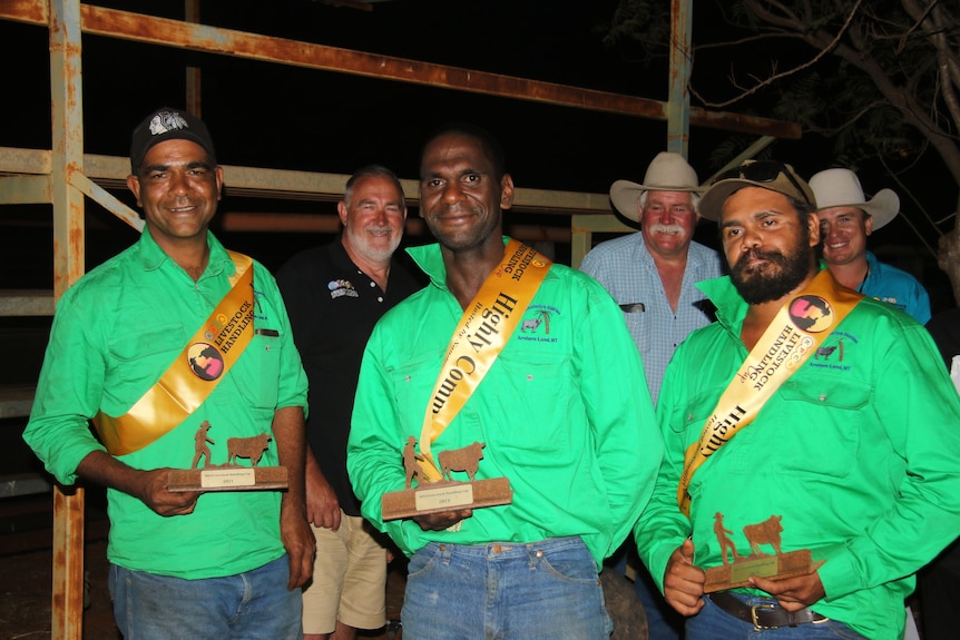 Three indigenous stockmen wearing green shirts and yellow sashes