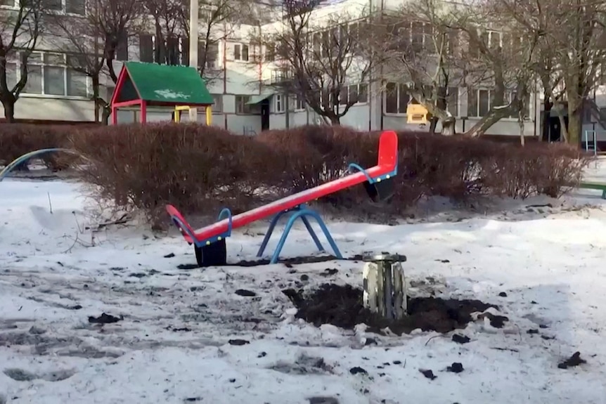 An unexploded rocket sits in the snow within a children's playground.
