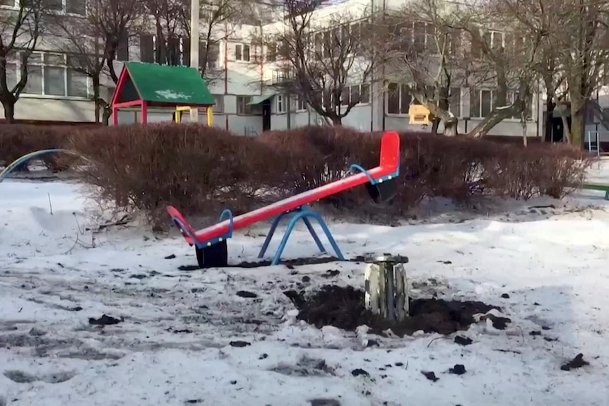 An unexploded rocket is lodged in the ground in front of a see-saw