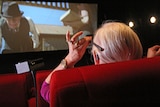A woman uses closed caption glasses in a cinema