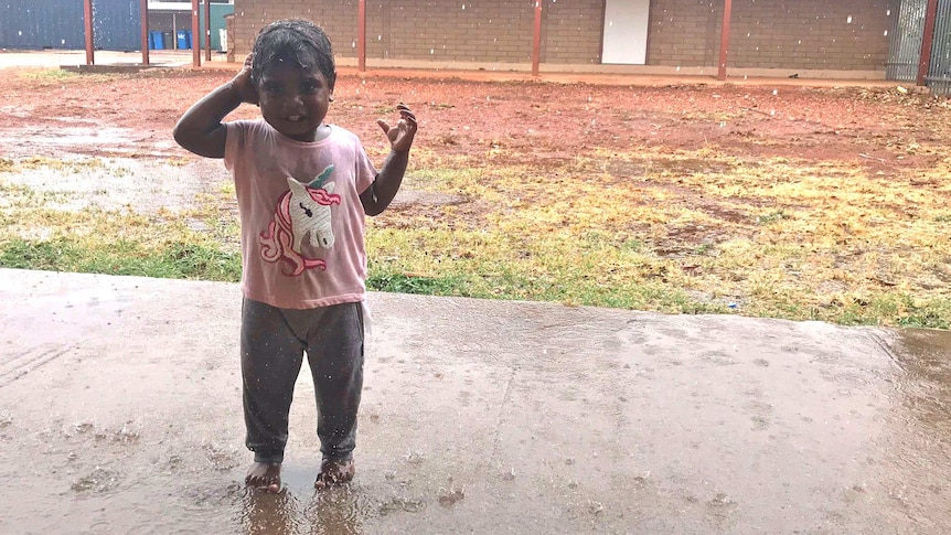 Rekiara stands in the rain in a unicorn t-shirt