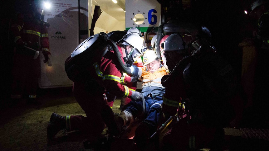 Miners in emergency gear around a stretcher.