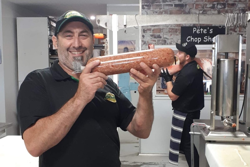 Pete Gianfrancesco holding a sausage in his chop shop