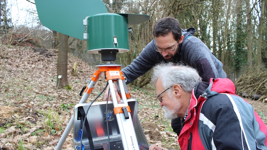 Two scientists monitor field equipment used to measure biodiversity