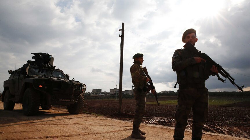 Turkey-backed Syrian fighters stand with guns and tank as they secure a checkpoint