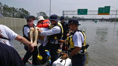A rescue team helps evacuate a woman who was trapped in her flooded home by Hurricane Katrina.