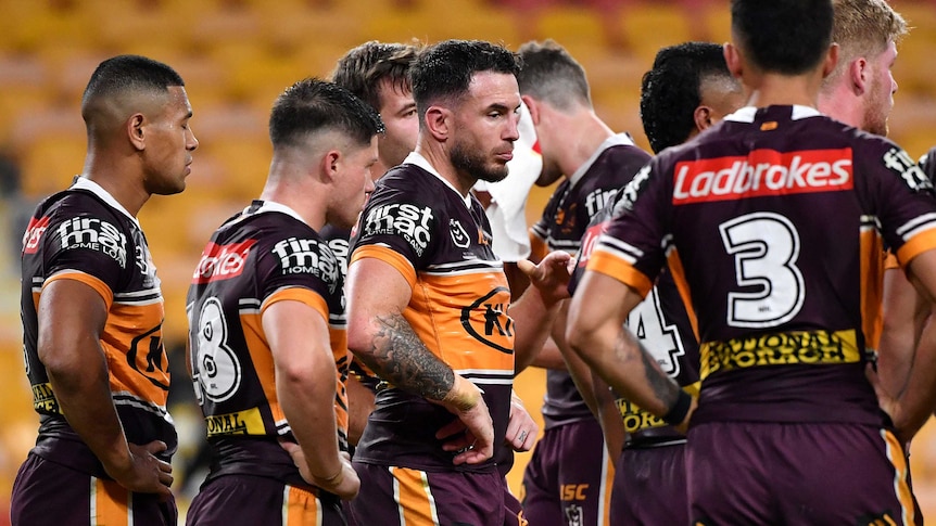 Brisbane Broncos players, with Darius Boyd front and centre, stand with their hands on their hips, looking disappointed.