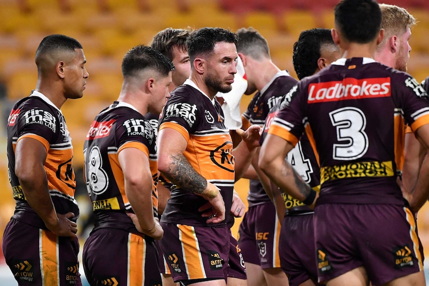 Brisbane Broncos players, with Darius Boyd front and centre, stand with their hands on their hips, looking disappointed.