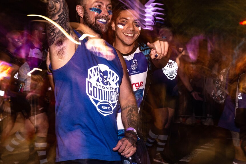 Deux hommes en maillot de football se tiennent souriant bras dessus bras dessous