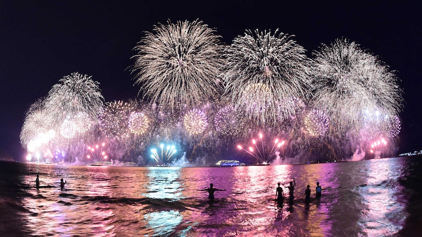 People take a dip in the sea during the fireworks for the new year on Copacabana beach