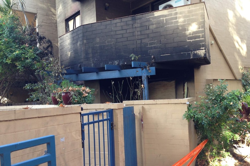 A cream-brick apartment with scorch marks from a fire.