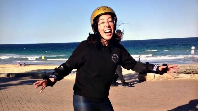 Eleanor Barz smiles while wearing rollerblades and a helmet.