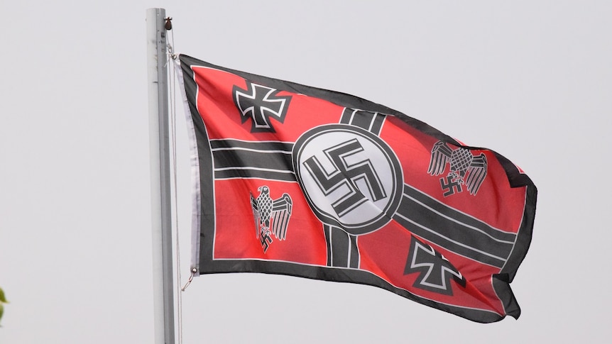 A black and red flag featuring the Nazi Swastika surrounded by four other symbols.