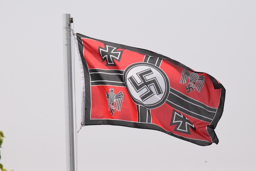 A black and red flag featuring the Nazi Swastika surrounded by four other symbols.