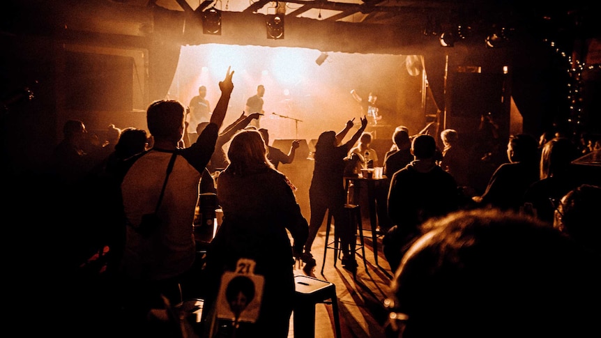 Punters gesture from their seats at the band, who are on stage in the distance