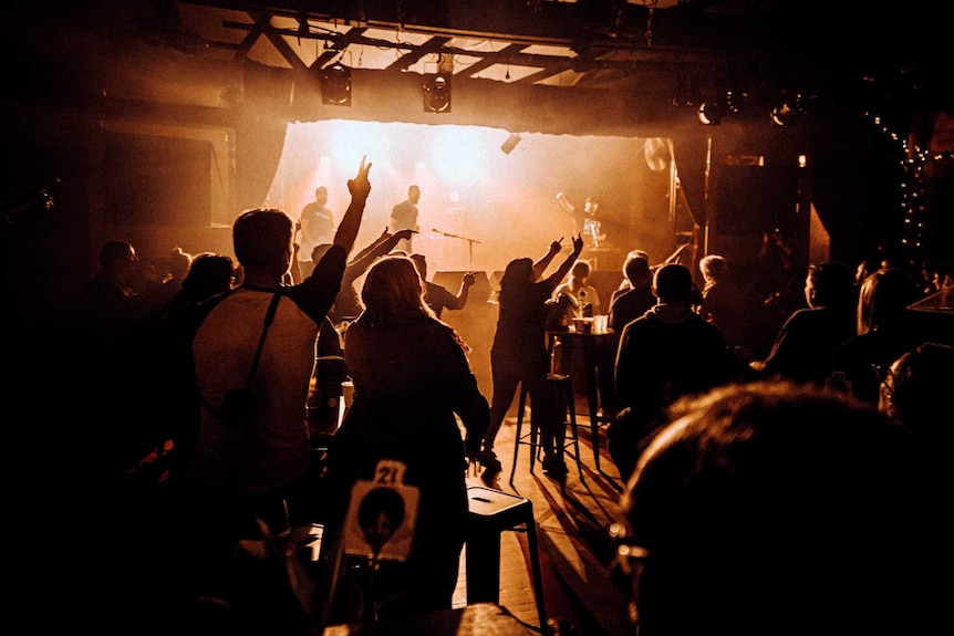 Punters gesture from their seats at the band, who are on stage in the distance