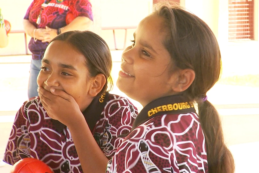 Two girls laughing as they take part in a school football program