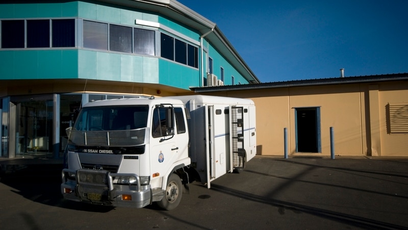 A white truck used for transporting prisoners sits outside the walls of Junee Correctional Centre.