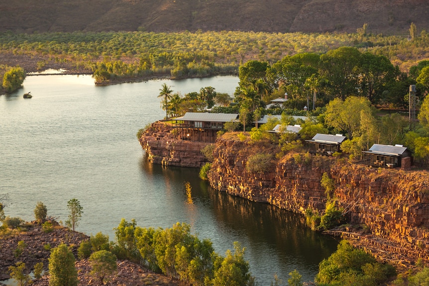 a homestead and accommodation along a cliff lining a river through an outback setting 