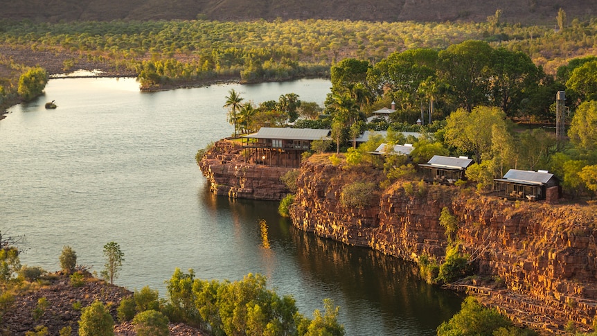 a homestead and accommodation along a cliff lining a river through an outback setting 