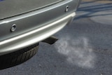 A car exhaust with visible fumes blowing out of it.
