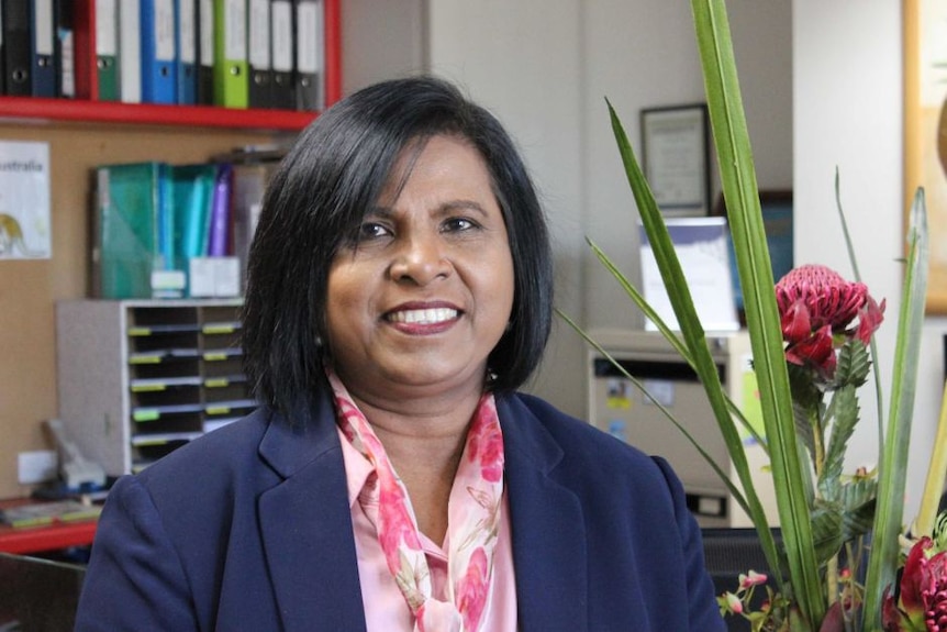 Dewani Bakkum sits in an office next to a plant smiling