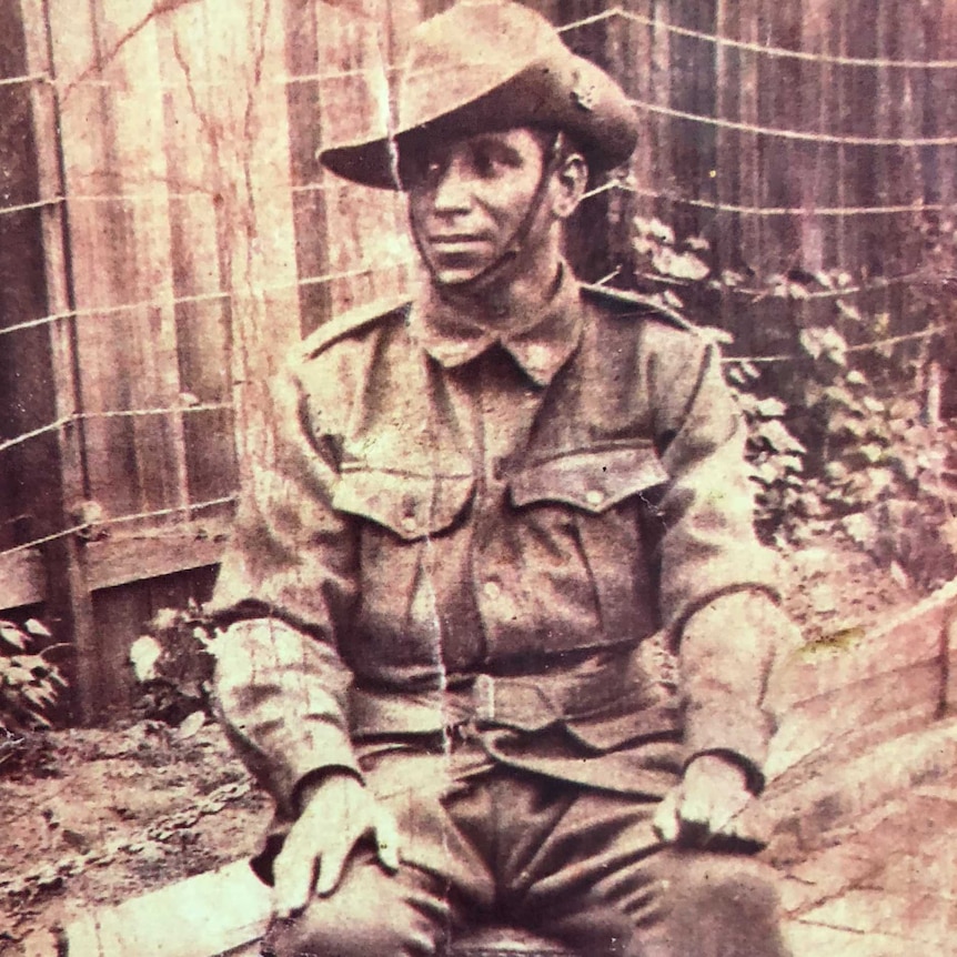 A man in Australian army uniform sits on a chair.
