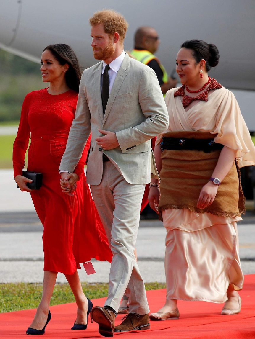 Prince Harry and Meghan with a Tongan prince on the tarmac.