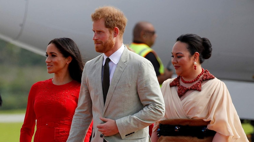 Prince Harry and Meghan with a Tongan prince on the tarmac.