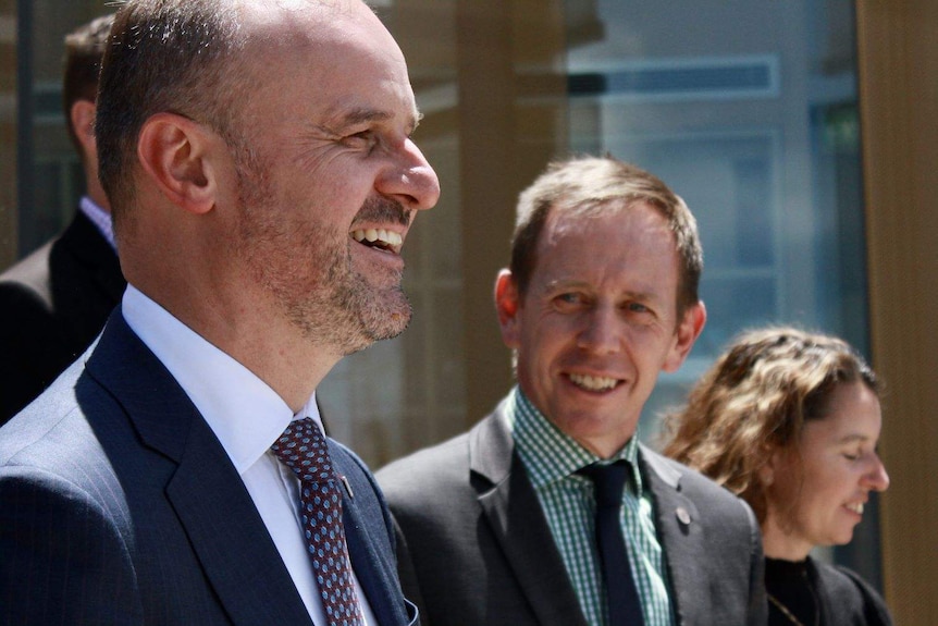 Andrew Barr and Shane Rattenbury stand on the steps outside the ACT Legislative Assembly, smiling.