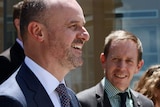 Andrew Barr and Shane Rattenbury stand on the steps outside the ACT Legislative Assembly, smiling.