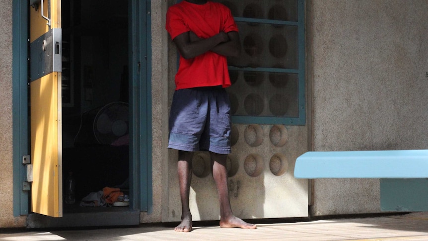 A young man stands outside a prison cell.