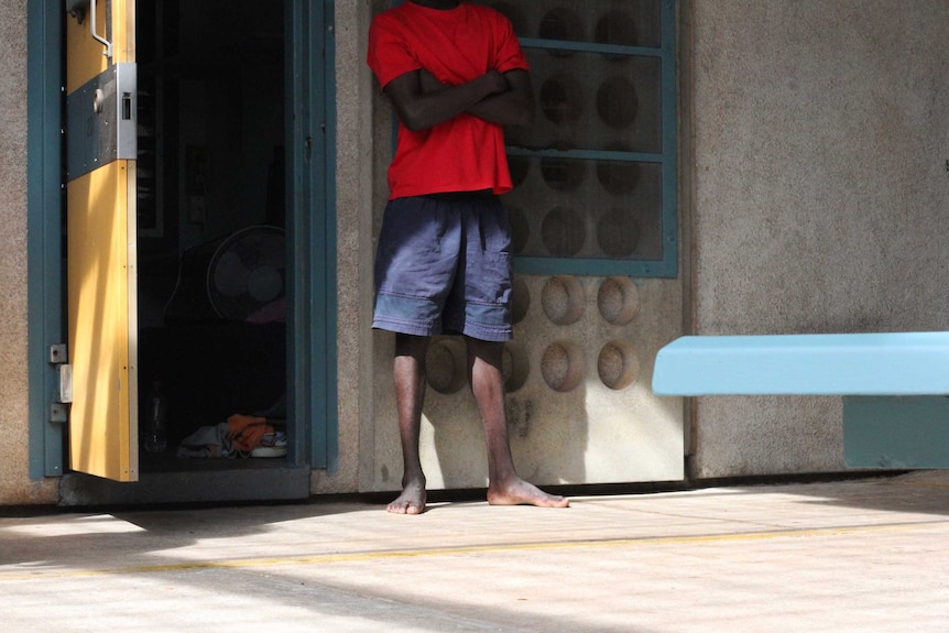 A young man stands outside a prison cell.