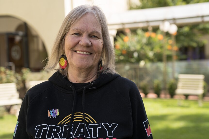 A woman in a 'treaty' jumper and Aboriginal flag earrings.