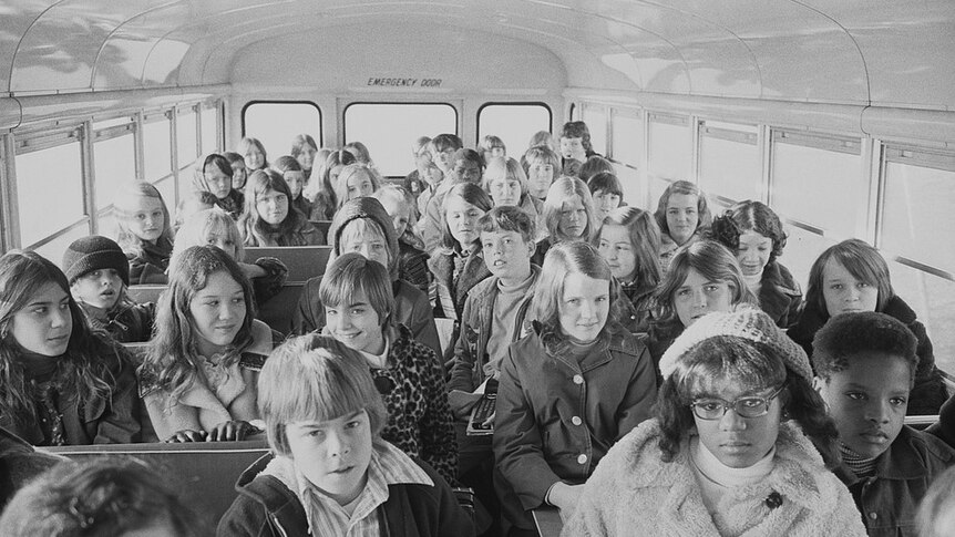 A black and white image of children crammed into a school bus