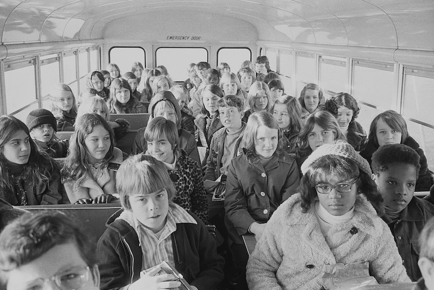 A black and white image of children crammed into a school bus