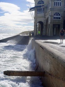 Waves lap a sea wall at the base of a building.