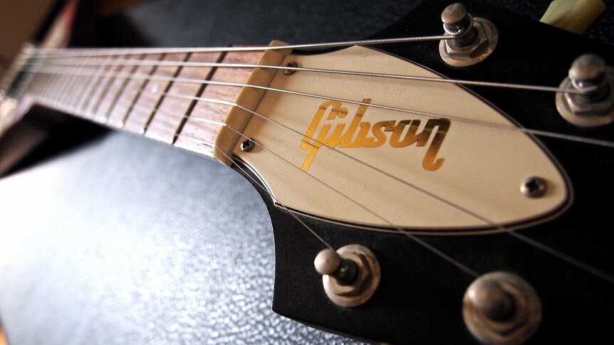 The Gibson guitar logo is shown up close on the guitar's head