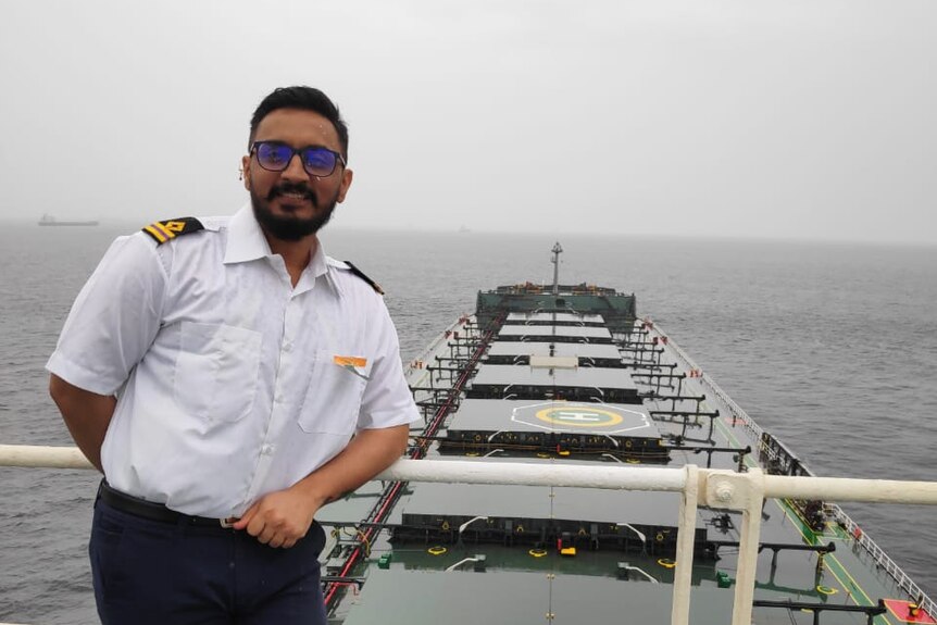 Virendrasinha Bhosale, an engineer on the bulk carrier Jag Anand, poses for a photo on deck. He is smiling.