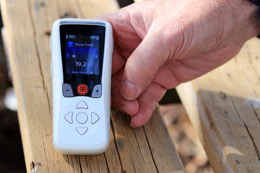 A close up photo of Dennis Shiller's hand holding his neuromodulation device.