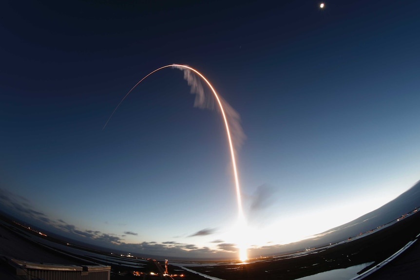 A long exposure of the Boeing Starliner launch shows a bight arching light in the sky.