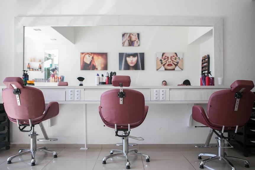 Three pink chair lined in front of a mirror at a hair salon