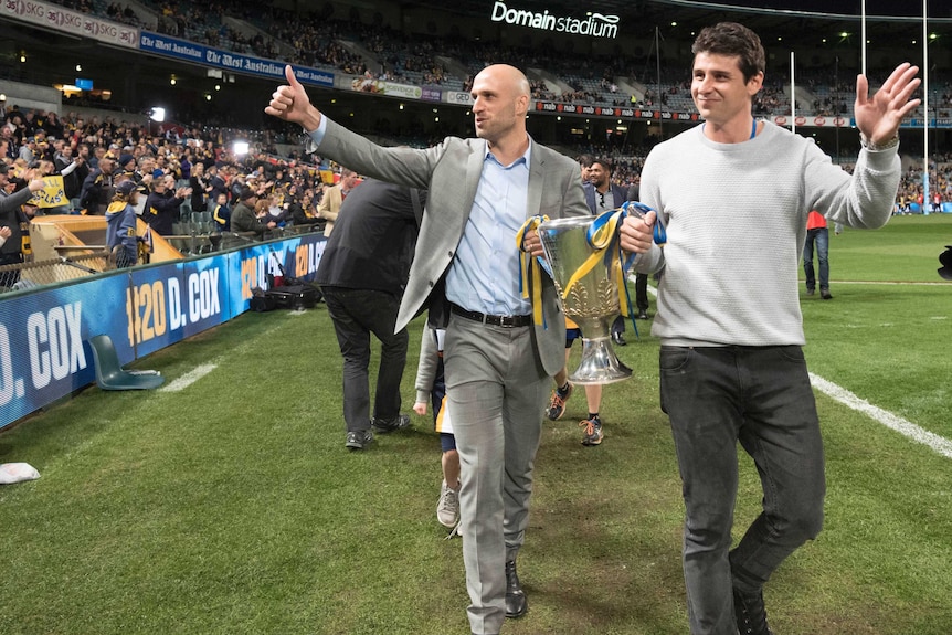 Chris Judd and Andrew Embley walk around Subiaco Oval holding the 2006 premiership cup.