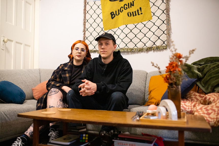 A young man and woman sit on a couch.