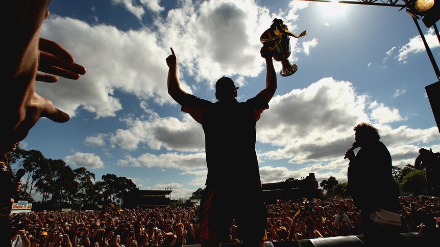 A silhouette of a man lifting a cup in the air.