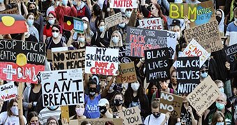 Protesters hold signs saying "I can't breathe" and "Black lives matter" in Australia.