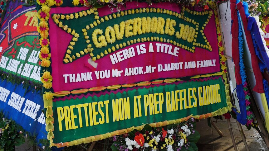 A red and green sign adorned with yellow flowers reads: 'Governor is job, hero is a title' 'thankyou mr ahok, mr djarot"