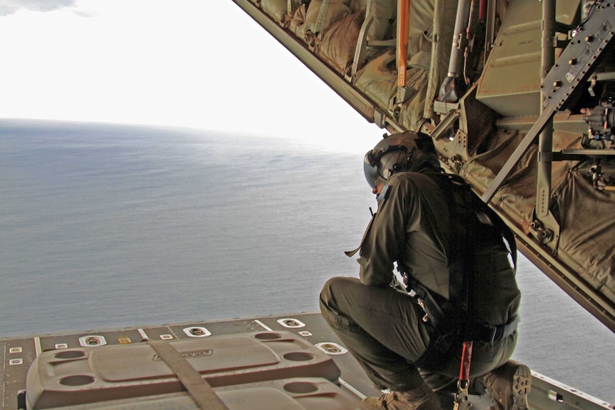 An airman crouching on the back of a C-130J Hercules